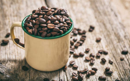 Coffee beans in a metal cup on a tableの写真素材