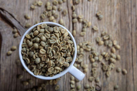 Green coffee beans in a cup on a wooden surfaceの写真素材