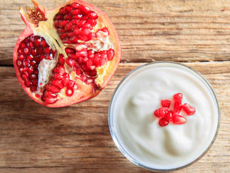 Pomegranate and yogurt on a wooden surfaceの写真素材