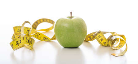 Green apple and a measuring tape on white backgroundの写真素材