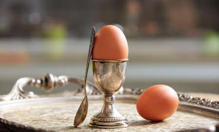Eggs and a silver egg cup in an old trayの写真素材