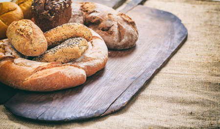 Variety of fresh baked breads on an old wooden surface