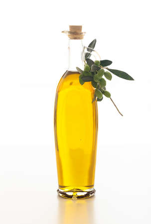 Olive oil in a bottle and an olive twig on white backgroundの写真素材