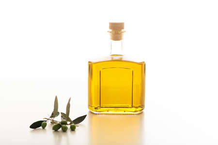 Olive oil in a bottle and an olive twig on white backgroundの写真素材