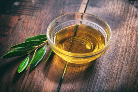 Olive oil and olive twig on a wooden surfaceの写真素材