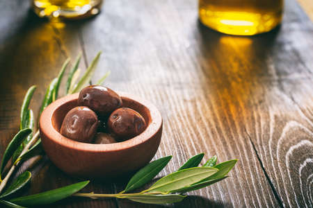 Olives and olive oil on a wooden tableの写真素材