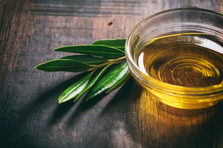 Olive oil and olive twig on a wooden surfaceの写真素材