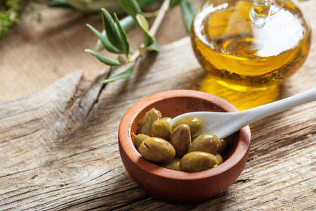 Olives and olive oil on a wooden tableの写真素材