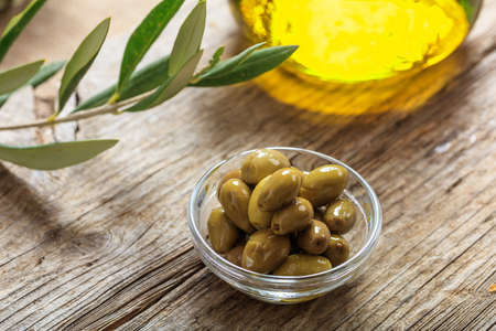 Olives and olive oil on a wooden tableの写真素材