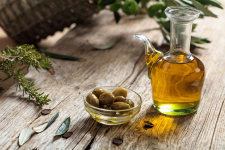 Olive oil and olive twig on a wooden tableの写真素材