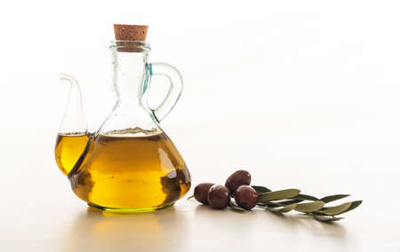 Olive oil in a bottle and an olive twig on white backgroundの写真素材