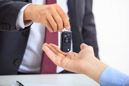Man in suit offering a car keyの写真素材