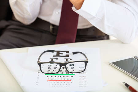 Eye vision test and a pair of glasses on a deskの写真素材