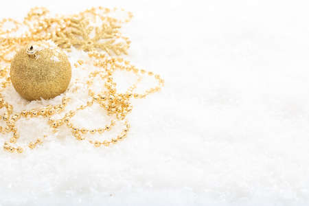 Golden christmas ball and snow on white backgroundの写真素材