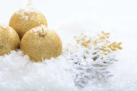 Golden christmas balls and snow on white backgroundの写真素材