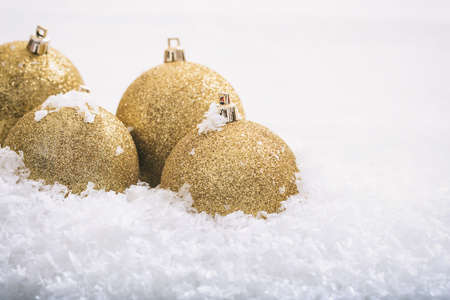 Golden christmas balls and snow on white backgroundの写真素材