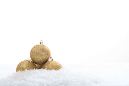 Golden christmas balls and snow on white backgroundの写真素材