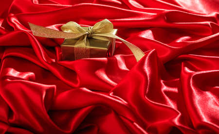 Golden gift box on a red satin backgroundの写真素材