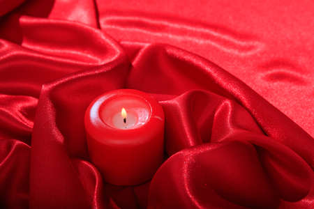 Candle on red satin backgroundの写真素材