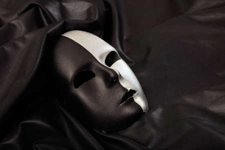 Black and silver carnival mask isolated on black satin backgroundの写真素材