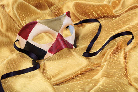 Harlequin carnival mask isolated on golden satin backgroundの写真素材