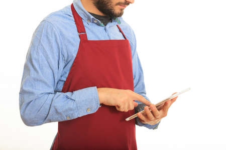 Young man with black apron taking an order on white backgroundの写真素材