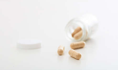 Capsules out of a bottle on white backgroundの写真素材