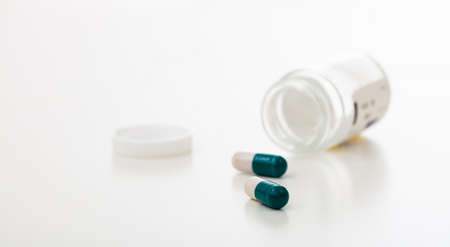 Capsules out of a bottle on white background