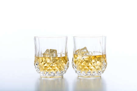 Crystal glasses of whiskey and ice on white backgroundの写真素材