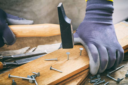 Carpenter with gloves working with a hammerの写真素材
