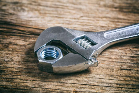 Wrench and nut on a wooden surfaceの写真素材