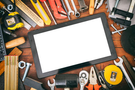 Variety of hand tools and tablet on a wooden table