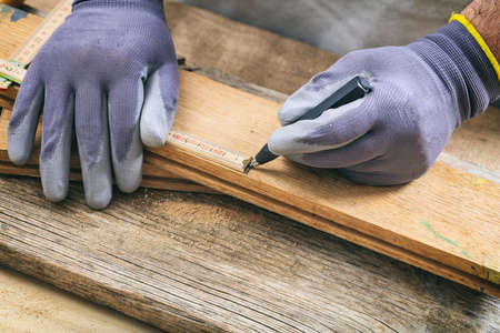 Man with gloves measuring with a wooden meterの写真素材