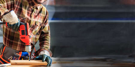 Worker holding an electric drill on blur black background