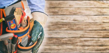Worker wearing tool belt and gloves on wooden backgroundの写真素材