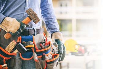 Worker with a tool belt holding a hammerの写真素材