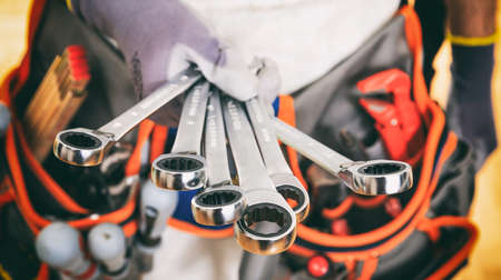 Worker with tool belt holding set of spannersの写真素材