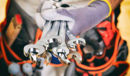 Worker with tool belt holding set of spannersの写真素材