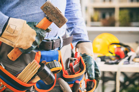 Worker with a tool belt holding a hammerの写真素材