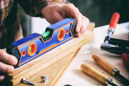 Carpenter holding a spirit level on a work benchの写真素材
