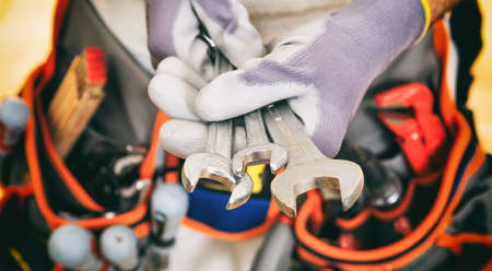 Worker with tool belt holding set of spannersの写真素材