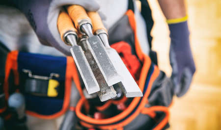 Worker with tool belt holding set of chiselsの写真素材