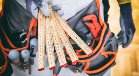 Worker with tool belt holding a wooden meterの写真素材