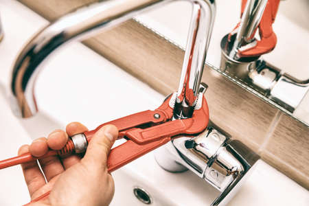 Hand of a person doing repair works with the tap. Horizontal indoors shot.の写真素材