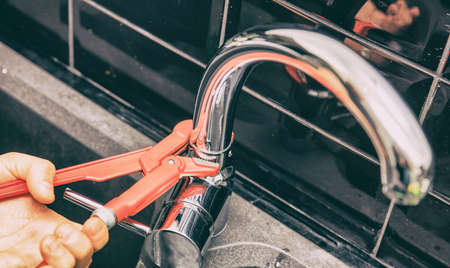 Hand of person tightening up a screw on a tap. Horizontal indoors shot.の写真素材