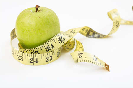 Green apple and measuring tape on white backgroundの写真素材