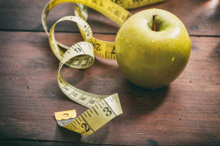 Green apple and measuring tape on wooden backgroundの写真素材