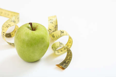 Green apple and measuring tape on white backgroundの写真素材