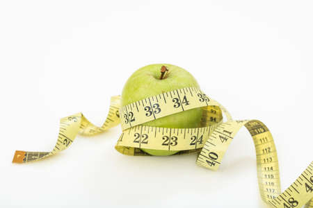 Green apple and measuring tape on white backgroundの写真素材