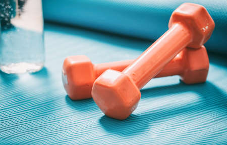 Dumbbells and a bottle of water on a green yoga matの写真素材